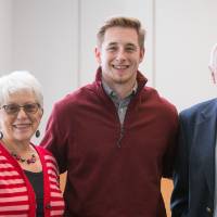 A student standing with his two donors.